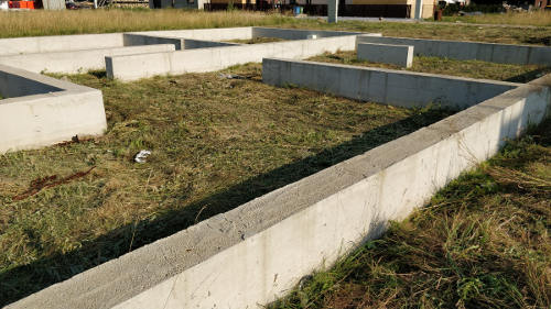 Paveikslėlis: nušienautas sklypas su pamatais